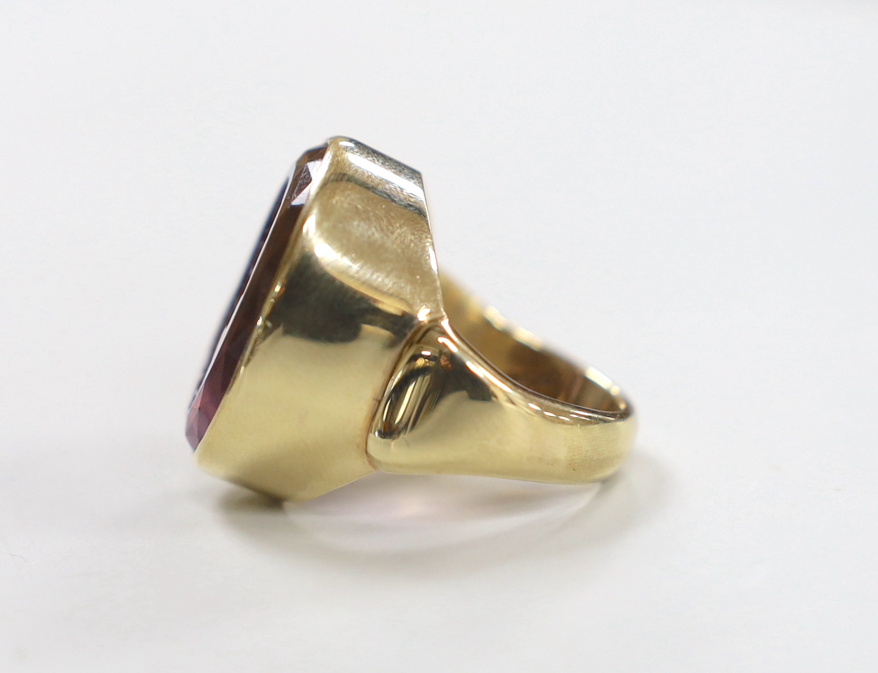 A modern 9ct yellow gold and amethyst intaglio set oval ring, carved with the head of a gentleman to sinister, size O, gross weight 18.2 grams.